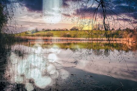 A pond with grass next to a body of waterの写真素材