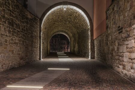 An old illuminated historic tunnel in the old town and old stones on the wallsの写真素材