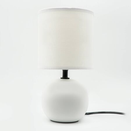 A modern table lamp with a white lampshade and a ceramic base, cut out on white backgroundの写真素材