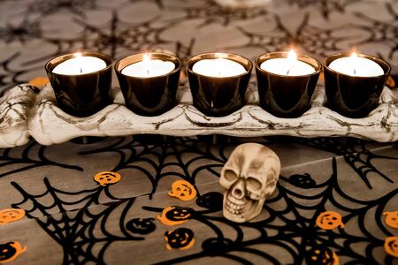 A bone with tea lights on it, skulls in the foreground and Halloween trimの写真素材