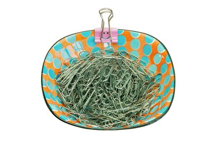 A porcelain bowl with paper clips and a pink smiley paper clip on the edge, white backgroundの写真素材