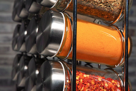 A metal spice rack with many glass bottles filled with different spices, studio shotの写真素材