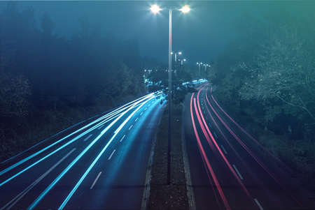 Long-exposure shot of a four-lane road with luminescent lights at the approachの写真素材