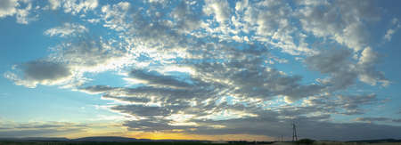 Panorama view on a moody yellow sunset between the clouds skyの写真素材