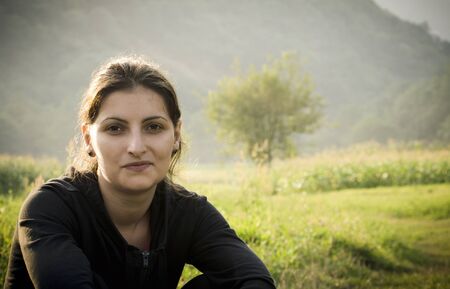 Young woman relaxing outdoor against mountain landscapeの写真素材