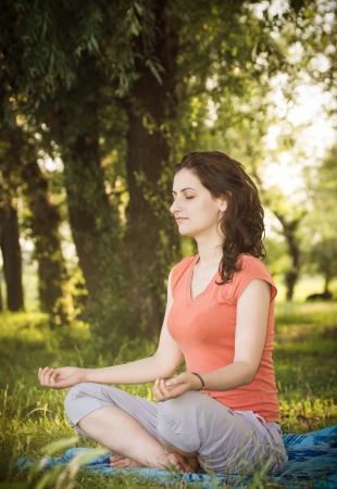 Young women in lotus position trying a breathing exercise in natureの写真素材