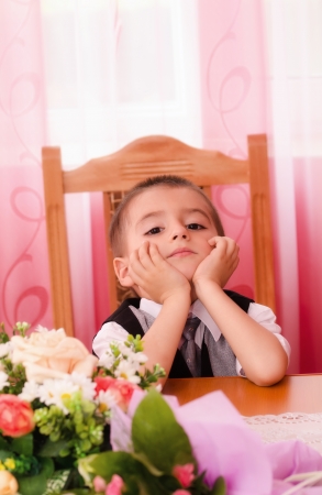 Little boy sitting on chair and thinkingの写真素材
