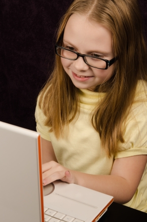Little girl  looks at laptop computer and having funの写真素材