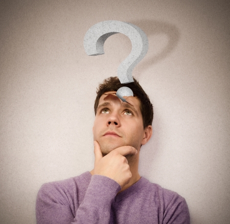 Young man lost in thought with a question mark leaving the headの写真素材