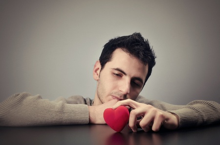 Young man looking at a heart with a sad lookの写真素材