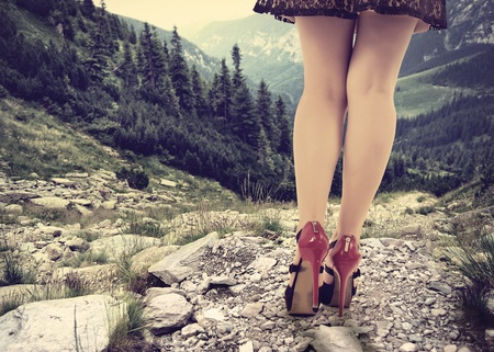 Concept with a women trying to climb down a mountain in elegant shoesの写真素材