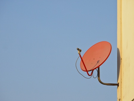 red satellite dish fix on building in sunlightの写真素材