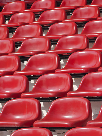 pattern of empty red stadium seats in sunlight