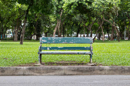 empty green bench at side of pathway in Lumphini Park, Bangkok Thailandの写真素材