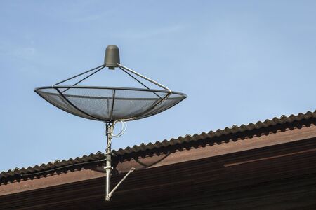 black satellite disk on roof of house in sunlightの写真素材