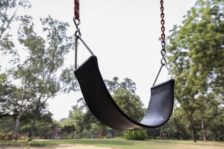 view of black seat swing in playground in sunlightの写真素材