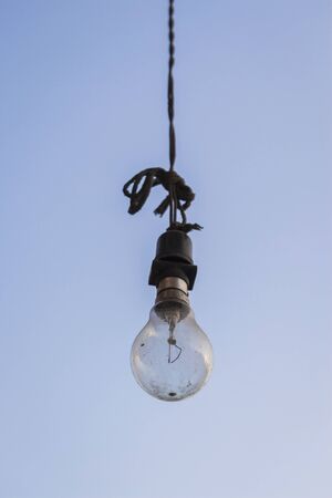 incandescent lamp hanging from high place in sky background