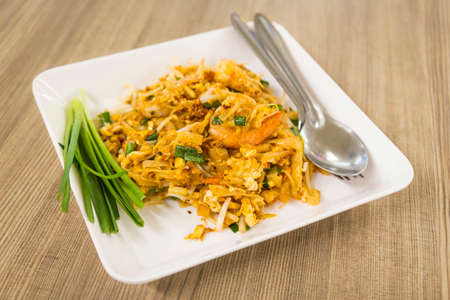 disk of Thai fried noodle with prawn on wooden tableの写真素材