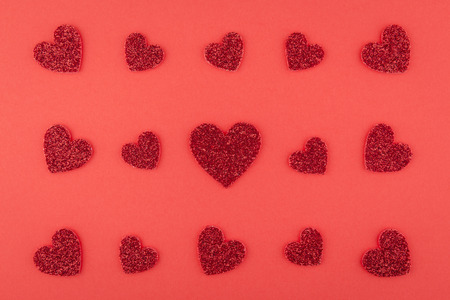 background of glitter red heart pieces array pattern on red paperの写真素材