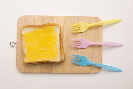 sweet toast butter on wooden chopping board with colorful fork on white background. this bread is thai style sweetmeat.の写真素材