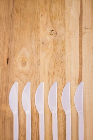 white plastic knife array decoration on wooden backgroundの写真素材