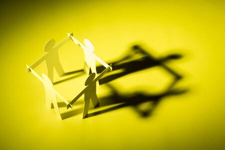 closed joining of four paper figure on yellow light background. in concept of business, cooperation...