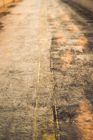 blur background of rough surface pathway with yellow line in sunlightの写真素材