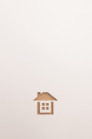 white background of paper cutout in complete house shape by brown wooden plate, for home and insurance conceptual.の写真素材
