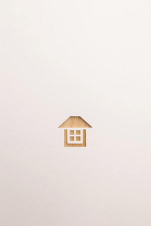paper cutout in complete house shape by brown wooden textured on white paper background, for home and insurance conceptual.の写真素材
