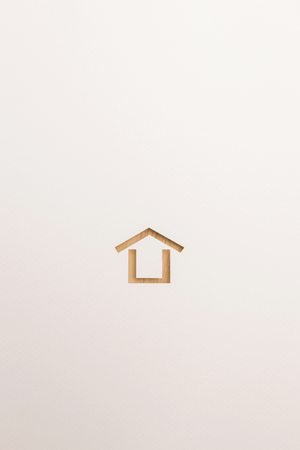 paper cutout in minimal house shape by brown wooden textured on white paper background, for home and insurance conceptual.の写真素材