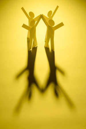 view of all in one joining of four both hand up paper figure on yellow light background. in concept of business, successful and enthusiasticの写真素材