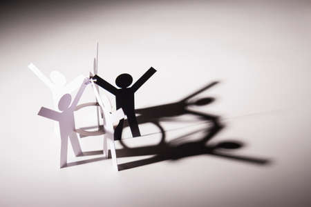 black figure in all in one joining of five both hand up paper figure on light background. in concept...