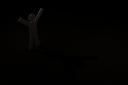 white paper cutout in hand up figure shape stand on light with shadow on black background, in concept of business, successful and  individuality.の写真素材