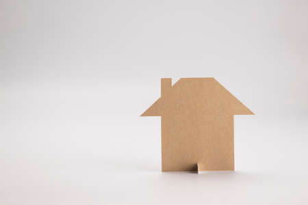 brown paper cutout in plain house shape on white background with copyspace, in concept of business banking and sustainability.の写真素材
