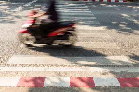 fast moving motorcycle across crosswalk line on road in bangkok, Thailand. in concepts of accident and road safety.の写真素材