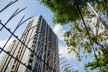 blur scene background of high condominium behind steel fence in daylight, location in bangkok,...