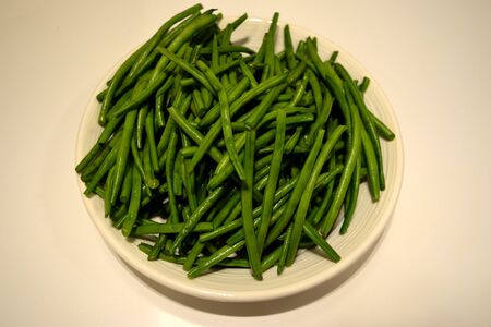 A closeup of a plate of raw green beans ready to be cookedの写真素材
