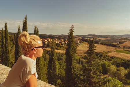 Tuscany, Italy. Beautiful blonde girl looking at a typical Tuscan landscape. Impressive image for the use you want to make of it.の写真素材