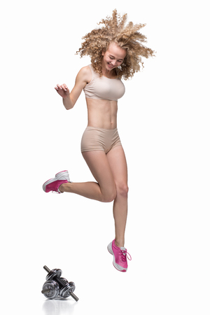 athletic girl jumping, isolated, with curly hairの写真素材
