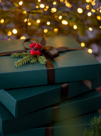 Christmas presents in green boxes with a bow near the tree with lights in the background. high quality photoの写真素材