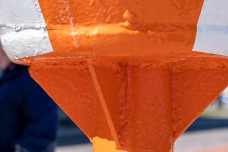 Robust, huge metal construction, painted bright orange with a white stripe. Fragment of bright orange sea navigation buoy. Blurred background. Copy space. High quality photoの写真素材