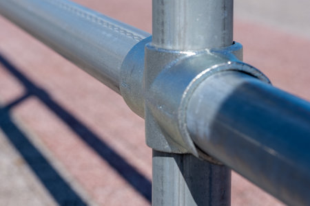 The shadow of metal pipes connected by fasteners on a light pink pavement on a sunny day. Copy space. Background for quotes. Advertisement for industrial constructions. High quality photoの写真素材