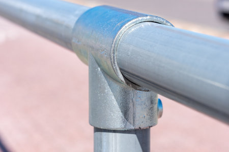 Metal pipe fastening with threads. In the background, a white stripe is painted on a light pavement in sunny summer day. Copy space. Background for quotes. High quality photoの写真素材