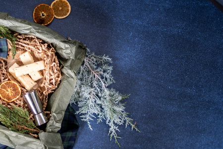 A box of Christmas gift cookies filled with shredded paper on a blue background. Alcohol jigger on a...
