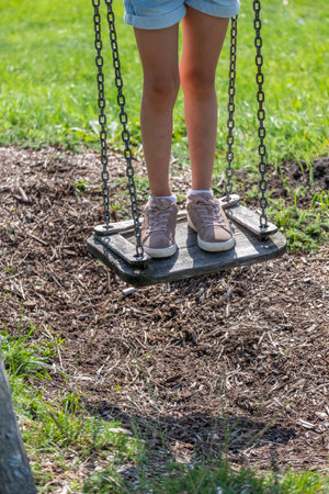 The focused view on a girls feet on a swing in a playground set evokes the essence of childhood play...