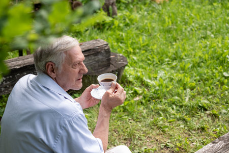 Elderly man sipping tea, with a focus on relaxation and the simplicity of enjoying nature, ideal for leisure and retirement, senior insurance concepts. High quality photoの写真素材