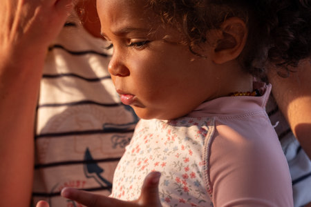 With soft curls framing a contemplative expression, this small child sucking on a thumb appears lost in thought, evoking themes of youth and reflection. High quality photoの写真素材