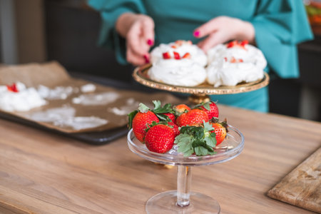 Close up of pavlova desserts, individual plating by a chef in green attire. Fits cooking class imagery. High quality photoの写真素材
