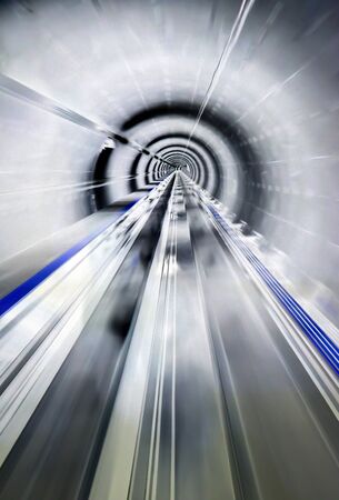 Zipping down a brightly lit silver train tunnel.の写真素材