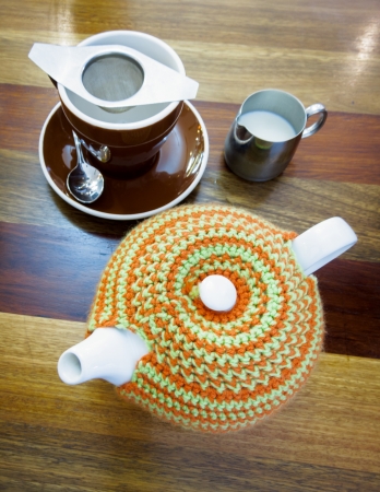 Cute tea set - teapot, teacup and saucer, and a jug of milk on a plain wood tableの写真素材